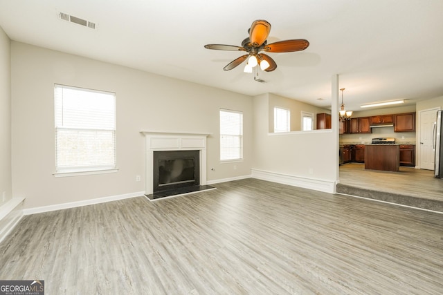 unfurnished living room featuring light wood-style floors, visible vents, baseboards, and a ceiling fan