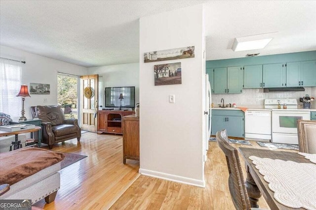 interior space featuring white appliances, a textured ceiling, open floor plan, light wood-type flooring, and under cabinet range hood