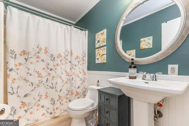 full bath featuring crown molding, wainscoting, wood finished floors, toilet, and a shower with shower curtain