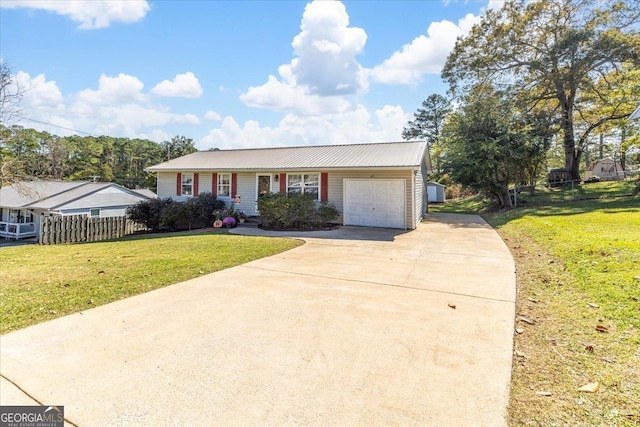 single story home with a garage, concrete driveway, fence, a front yard, and metal roof