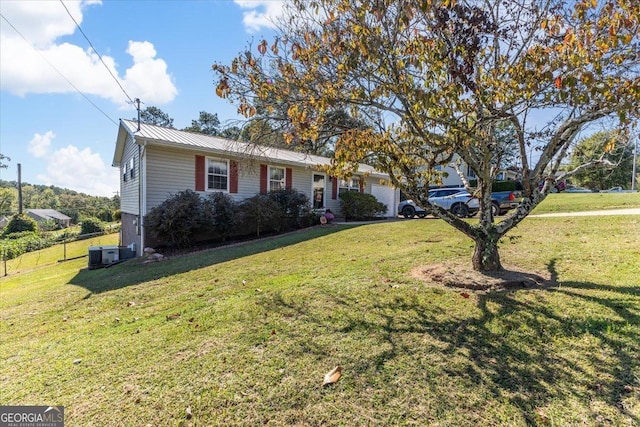 ranch-style home with fence, a front yard, cooling unit, metal roof, and an attached garage