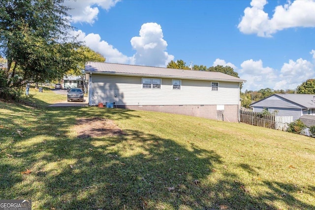 back of property featuring a lawn, fence, and metal roof
