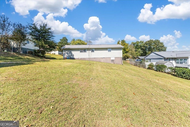 back of house featuring fence, a yard, and metal roof