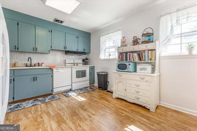 kitchen featuring white appliances, blue cabinetry, ventilation hood, and light wood-style flooring