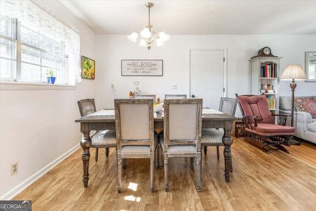 dining space featuring baseboards, a notable chandelier, and wood finished floors