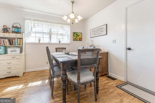 dining room featuring baseboards, an inviting chandelier, wood finished floors, and visible vents