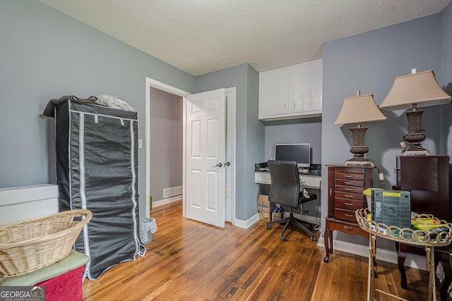 home office with visible vents, baseboards, and wood finished floors