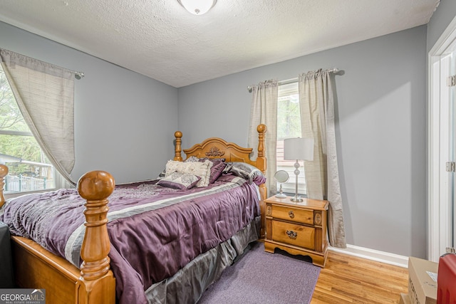 bedroom featuring baseboards, wood finished floors, and a textured ceiling