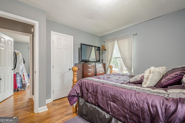 bedroom featuring a textured ceiling, baseboards, and wood finished floors
