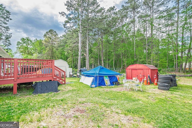 view of yard with a shed, a swimming pool, a wooden deck, and an outbuilding