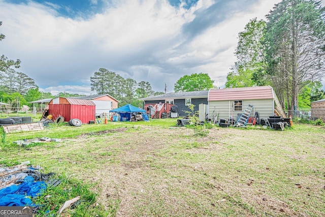 view of yard featuring an outbuilding, fence, and a storage unit