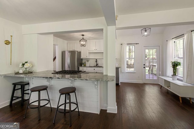 kitchen with a sink, white cabinets, a breakfast bar area, and stainless steel appliances