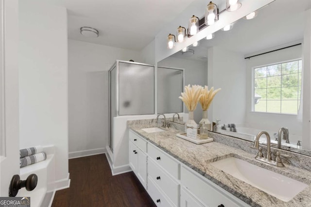 bathroom with a stall shower, wood finished floors, and a sink