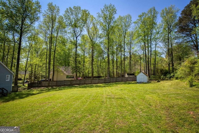 view of yard with a shed, an outdoor structure, and fence