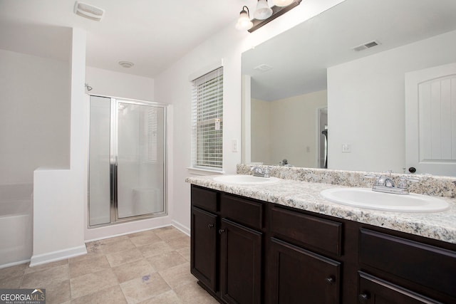 bathroom featuring a stall shower, double vanity, a sink, and visible vents