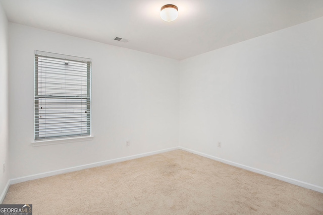 empty room featuring carpet, visible vents, and baseboards