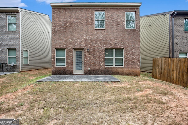 rear view of property with a patio area, brick siding, a yard, and fence