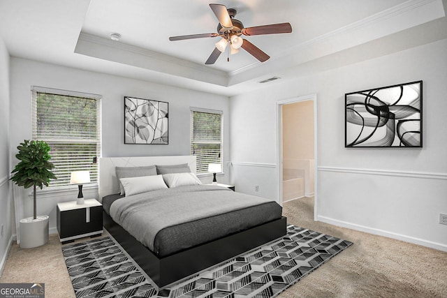 carpeted bedroom featuring ornamental molding, baseboards, a raised ceiling, and visible vents