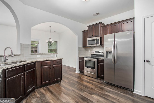 kitchen featuring arched walkways, visible vents, dark wood-style flooring, a sink, and stainless steel appliances