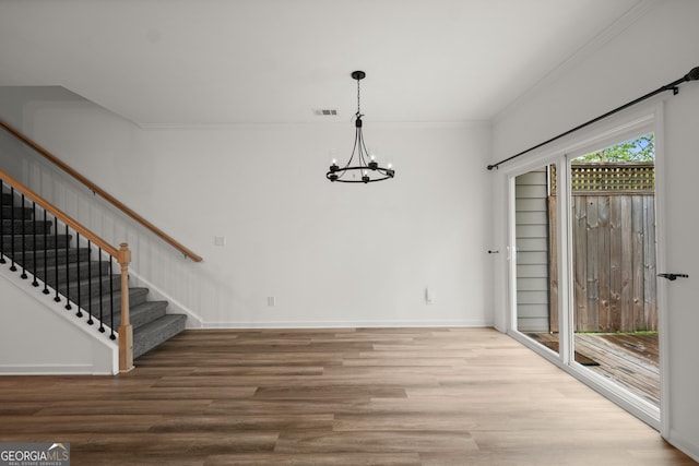 unfurnished dining area featuring crown molding, visible vents, stairway, wood finished floors, and a notable chandelier