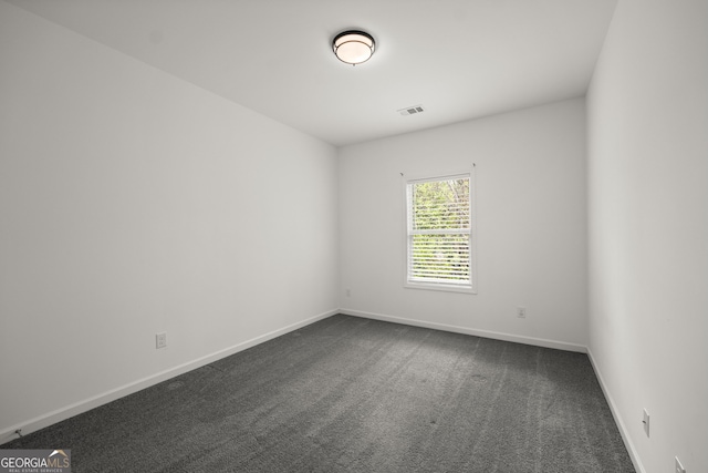 spare room with dark carpet, baseboards, and visible vents