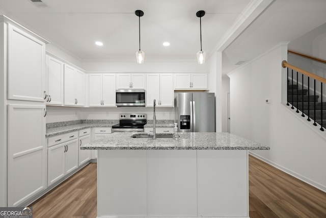 kitchen with an island with sink, light wood-style flooring, white cabinetry, light stone countertops, and appliances with stainless steel finishes