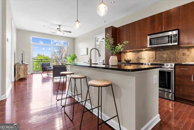 711 Cosmopolitan Dr NE Unit 347, Atlanta, GA 30324 - kitchen featuring tasteful backsplash, a sink, a kitchen breakfast bar, dark wood-style floors, and stainless steel appliances