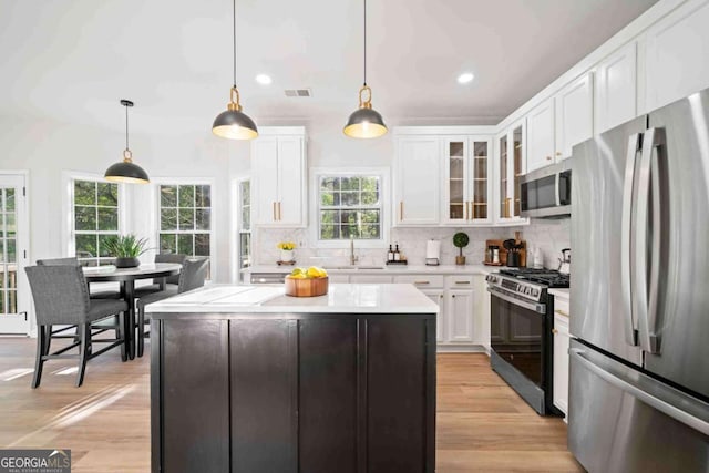kitchen featuring appliances with stainless steel finishes, light countertops, white cabinets, tasteful backsplash, and recessed lighting
