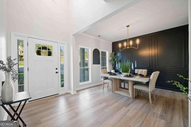 foyer entrance with light wood-style flooring, a chandelier, ornamental molding, and baseboards