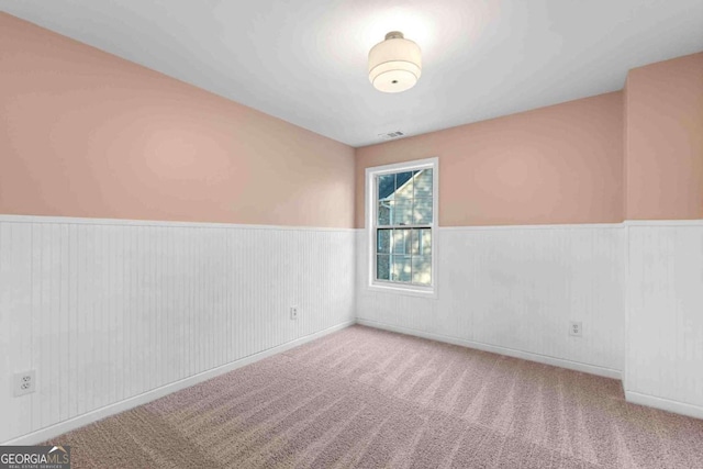 unfurnished room featuring wainscoting and carpet floors