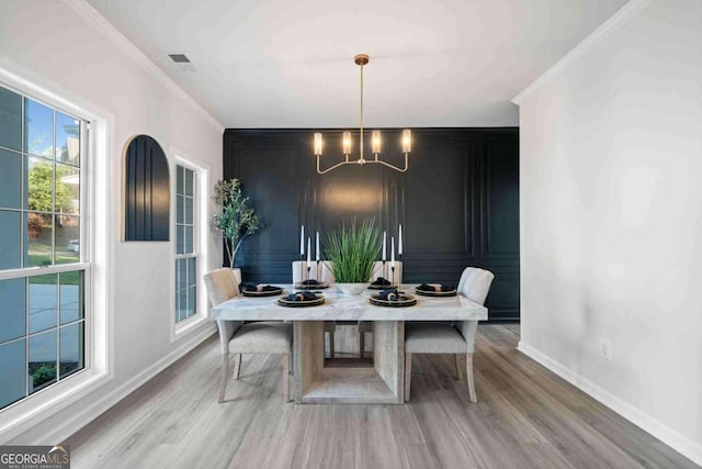 dining area with a chandelier, baseboards, wood finished floors, and crown molding