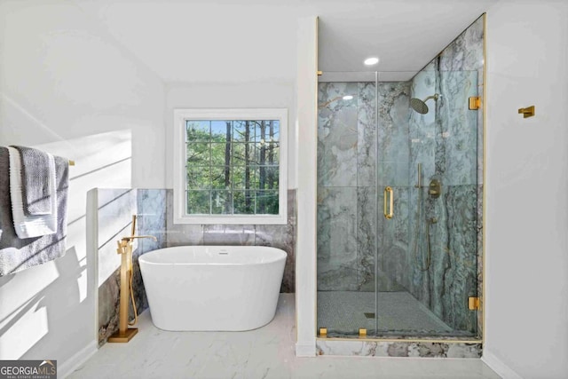 bathroom featuring marble look tiles, a marble finish shower, and a freestanding bath