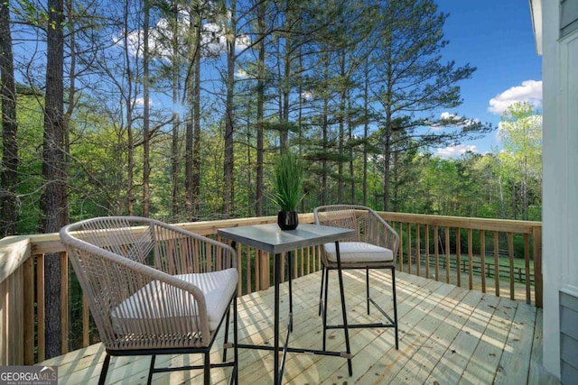 wooden deck featuring outdoor dining area and a view of trees