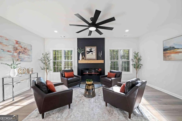 living room with plenty of natural light, wood finished floors, a large fireplace, and recessed lighting