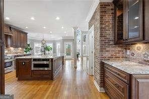 kitchen featuring an island with sink, dark brown cabinetry, ornamental molding, oven, and decorative backsplash