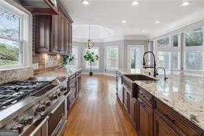 kitchen featuring double oven range, crown molding, light stone counters, and a healthy amount of sunlight
