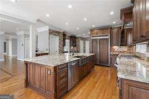 kitchen featuring a large island, light stone counters, paneled built in fridge, light wood-style floors, and stainless steel dishwasher