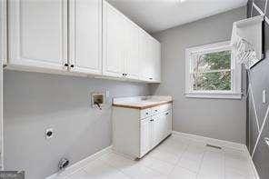 laundry area with washer hookup, baseboards, cabinet space, and light tile patterned floors