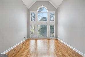 unfurnished room with wood finished floors, baseboards, and vaulted ceiling
