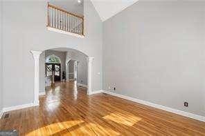interior space featuring baseboards, ornate columns, arched walkways, and wood finished floors