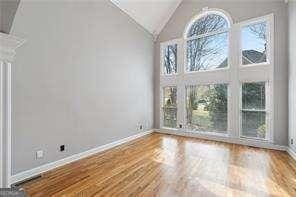 spare room featuring wood finished floors, baseboards, and lofted ceiling