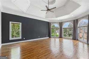 unfurnished room with coffered ceiling, wood finished floors, ceiling fan, and baseboards