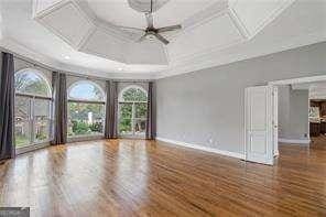 empty room featuring baseboards, wood finished floors, and coffered ceiling