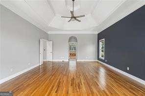 spare room with baseboards, wood finished floors, coffered ceiling, and ceiling fan