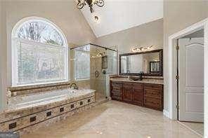 full bath featuring a bath, a shower stall, vanity, vaulted ceiling, and tile patterned floors