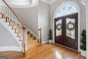 entryway with baseboards, ornamental molding, stairway, wood finished floors, and french doors