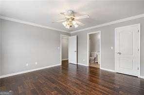 unfurnished bedroom featuring crown molding, baseboards, a ceiling fan, and ensuite bath