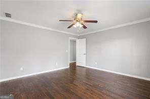 spare room featuring wood finished floors, baseboards, crown molding, and ceiling fan