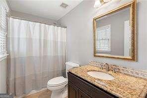 bathroom with toilet, a shower with shower curtain, and vanity