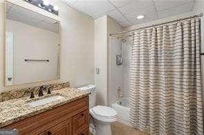 bathroom featuring toilet, a drop ceiling, vanity, and shower / bath combination with curtain